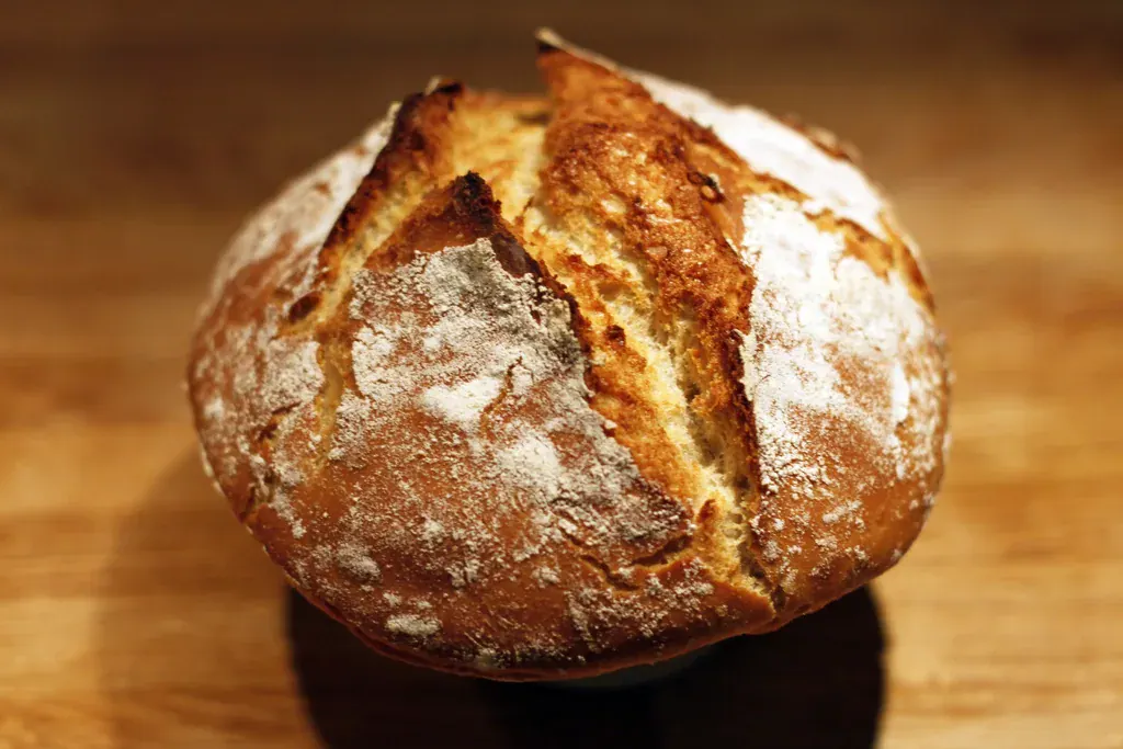Pão rústico de casca crocante sobre uma tábua de madeira
