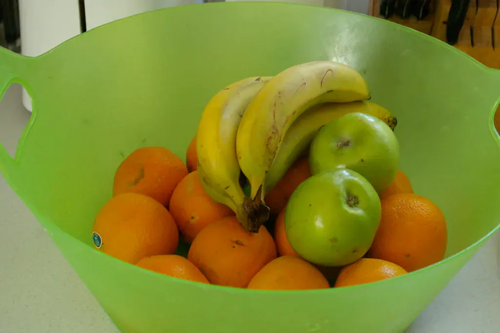 Bacia verde com bananas, maçãs verdes e laranjas