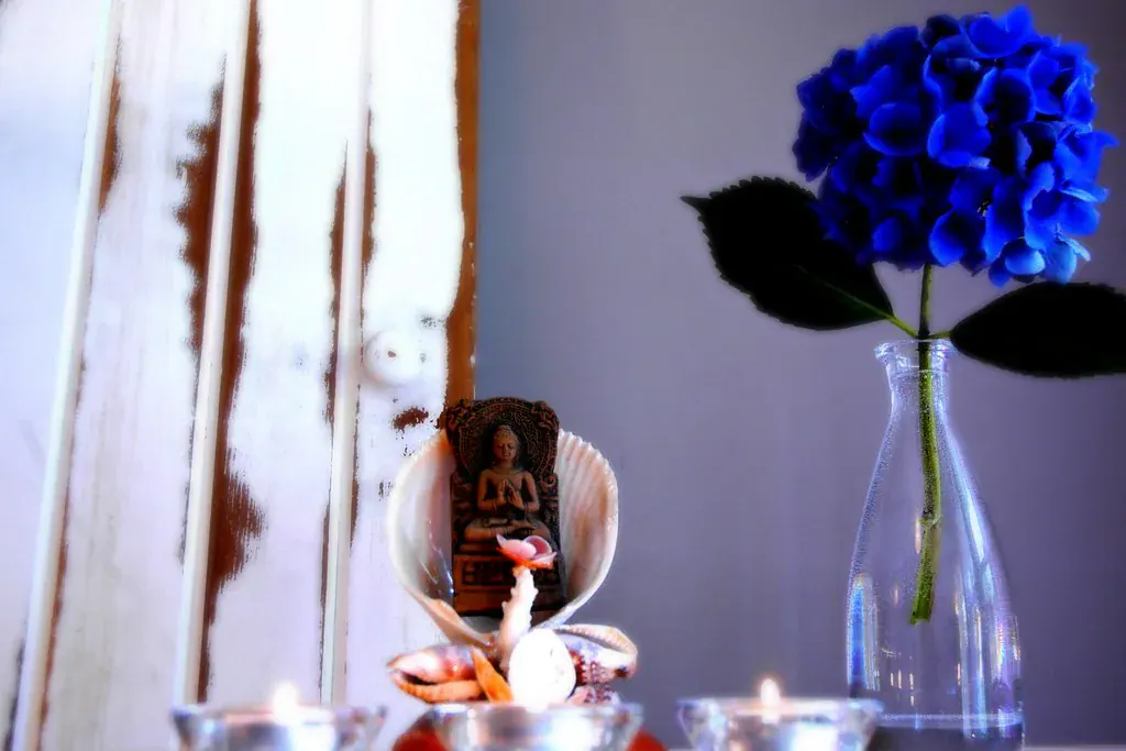 Hortênsia azul num vaso de vidro ao lado de velas acesas
